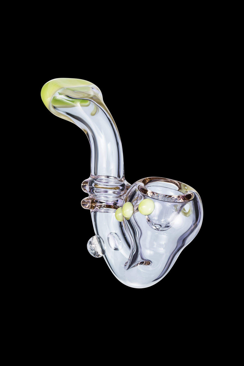 Angled close-up of the Maria Ring Sherlock Pipe showing its clear glass body with teal-green mouthpiece and three small pinkish-yellow accent knobs against a black background