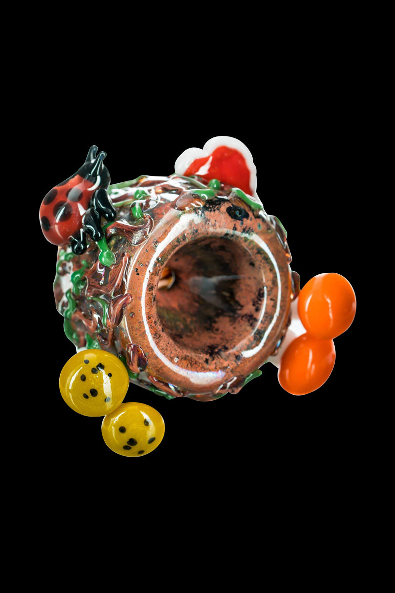 Top-down view of the Empire Glassworks "Bug's Life" Bowl showing a hollow, textured brown glass body with a ladybug, green vines, orange bubbles, and yellow spotted accents against a black background.