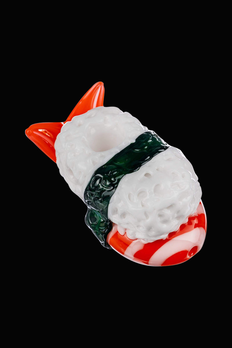A studio shot of the Empire Glassworks Shrimp Nigiri Sushi Hand Pipe, appearing as a miniature, colorful sushi roll against a plain black backdrop.