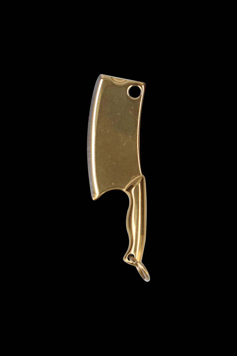 Close-up front view of the gold THGC EX II Mini Chopping Knife with Cover suspended against a black background, showing its curved blade, finger groove handle, and keyring hole.