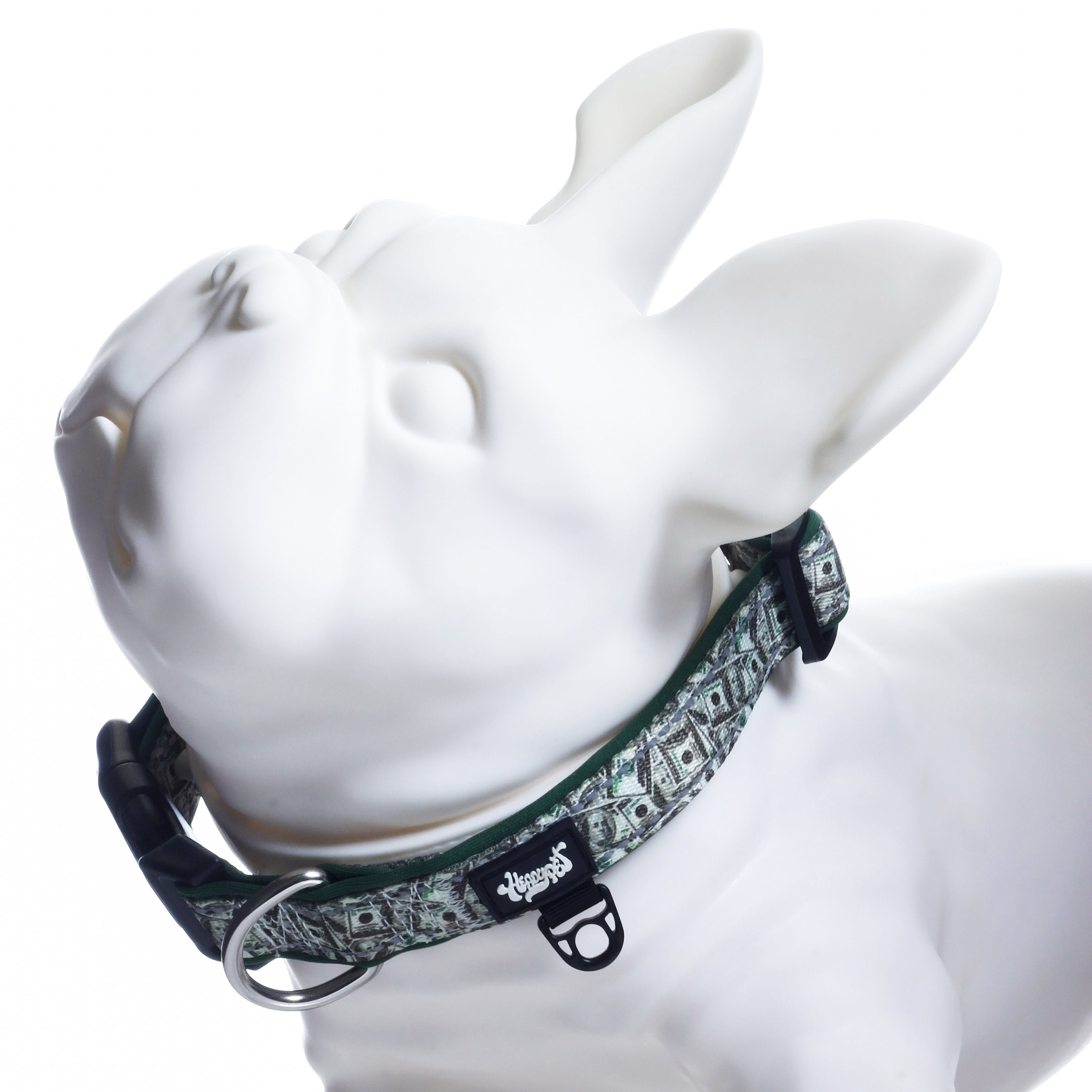 Close-up angled view of a white mannequin wearing the HeadyPet Collar V2 showing the patterned Rasta-style strap, metal D-ring, and black quick-release buckle.