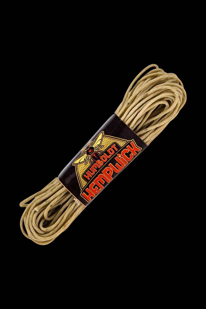 A close-up, angled view of the Humboldt Hemp Wick Full Flame, showing the tightly coiled, natural hemp cord against a dark background.