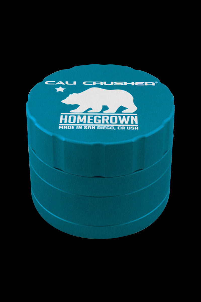Close-up angled view of a purple Cali Crusher Homegrown 4-Part Grinder against a black background, showing its stacked ridged layers and white bear logo.