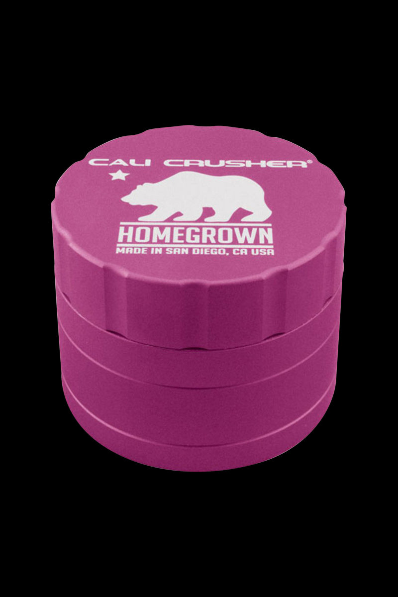 Top-down view of a magenta Cali Crusher Homegrown 4-Part Grinder with white bear logo and scalloped lid against a black background