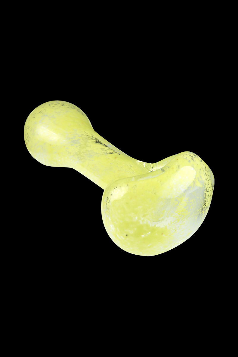 Diagonal close-up of a yellow, speckled Glassheads Spoon Pipe with Scatter Frit against a solid black background