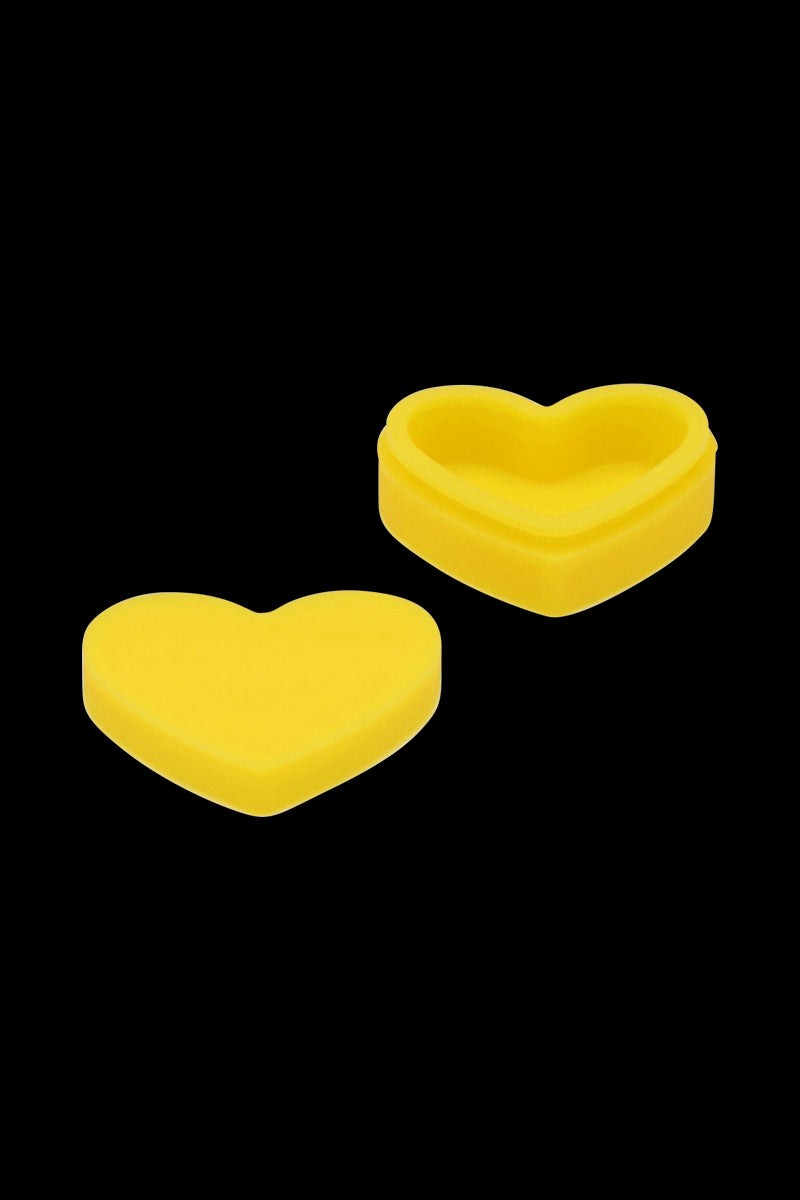 Top-down view of a bright yellow Silicone Heart Stash Container showing one open heart-shaped base and its matching lid on a black background