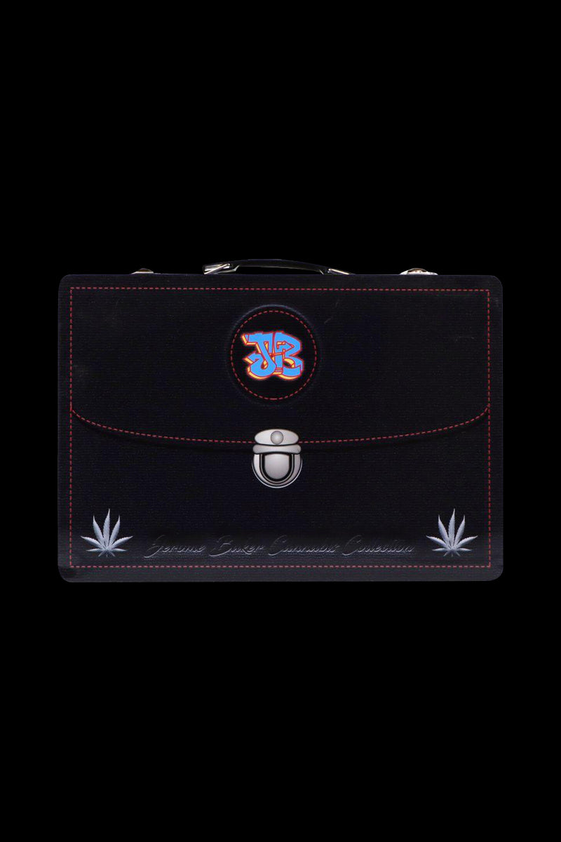 Front-facing shot of a black Jerome Baker Lunch Box with red stitching, round colorful logo near the handle and silver clasp centered on a black background
