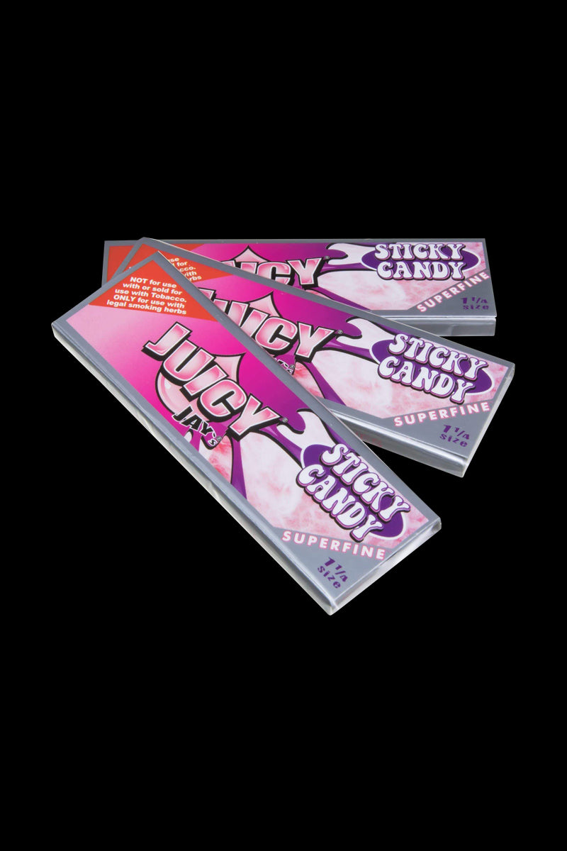 A stack of Juicy Jay's Superfine 1-1/4" flavored rolling papers is shown at a slight angle against a dark background.