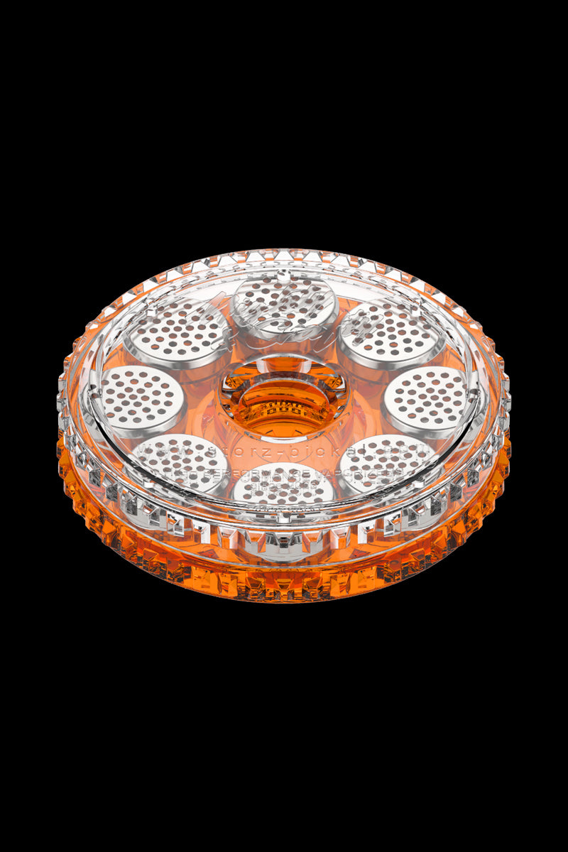 Top-down view of the clear and orange Storz & Bickel Dosing Capsules - 40 Pack arranged in a circular holder against a black background.