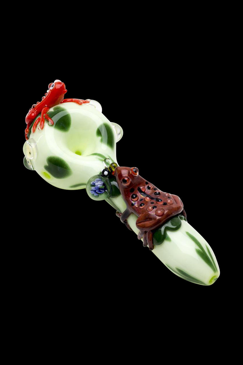 Angled view of the Empire Glassworks Ribbit Small Spoon Pipe showing a pale green bowl with dark green spots and two sculpted red and brown frogs.