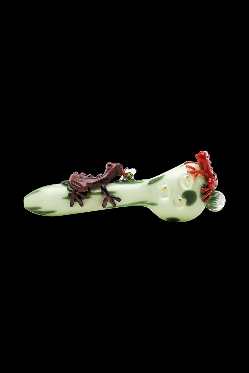 Side view of the Empire Glassworks Ribbit Small Spoon Pipe showing a pale green glass spoon with dark green spots and small brown and red frog figures on top.