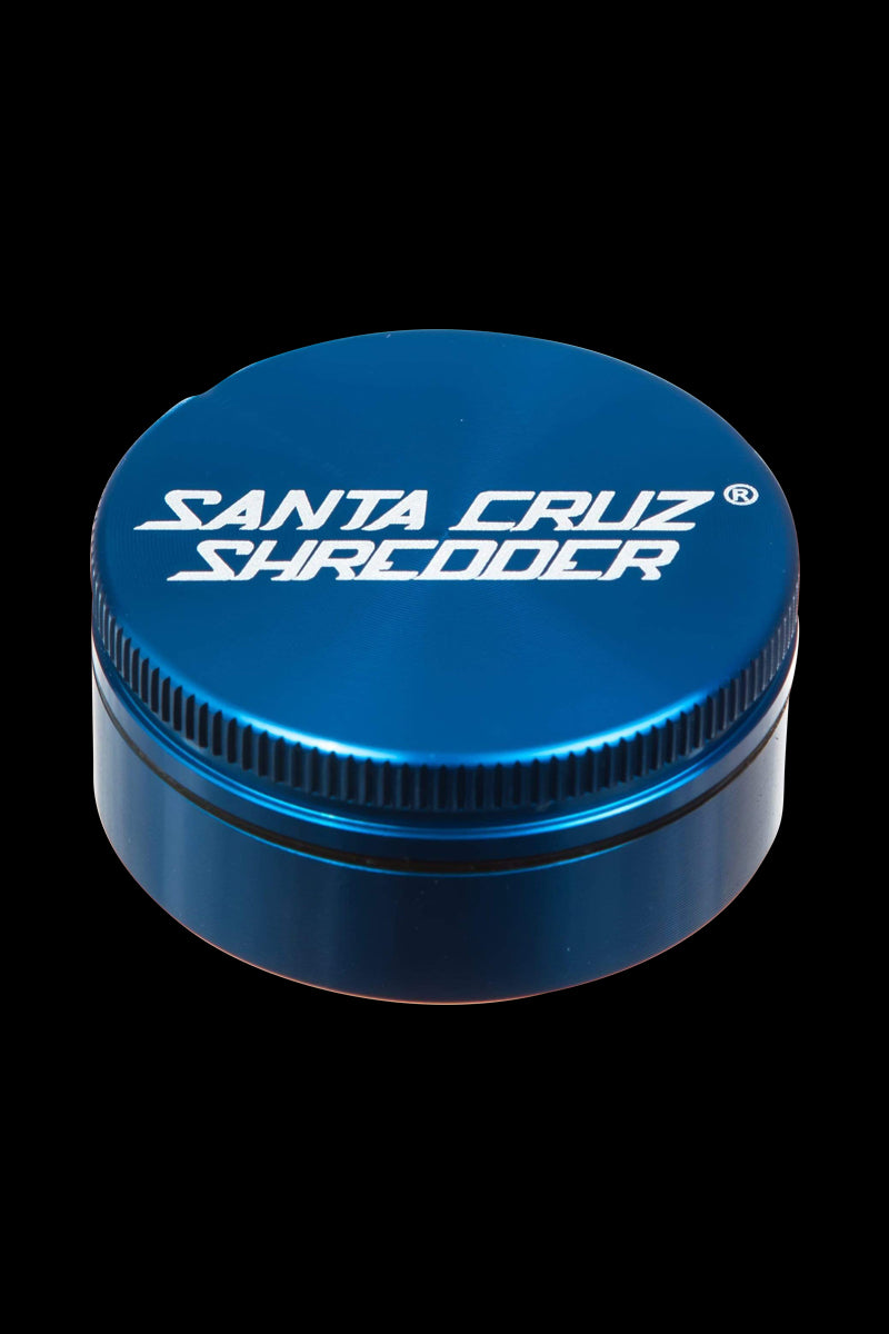 A close-up, angled view of the Santa Cruz Shredder Small 2-Piece Grinder, showcasing its metallic blue, cylindrical design.