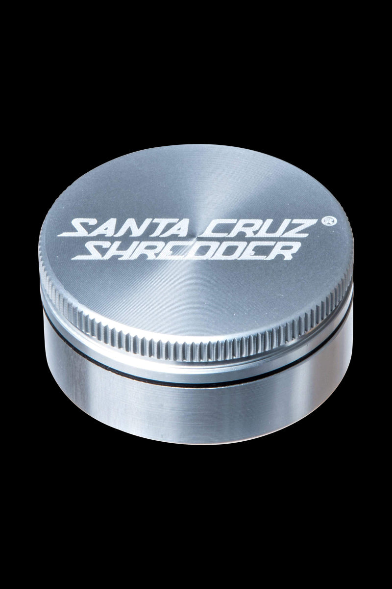 A close-up, angled view of the Santa Cruz Shredder Small 2-Piece Grinder, showcasing its metallic, cylindrical form and textured top.