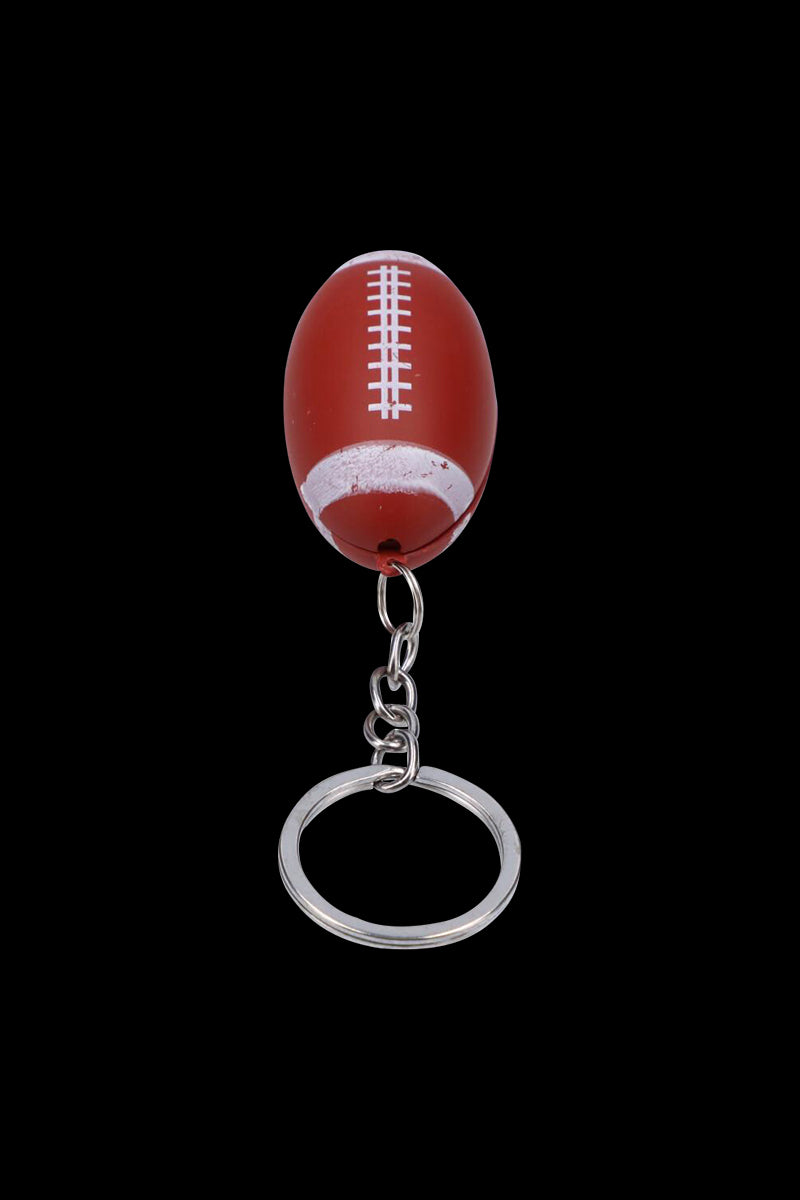 Centered close-up of the American Football Metal Hand Pipe with Key Chain, a small red football-shaped pipe hanging from its silver chain and split ring against a black background