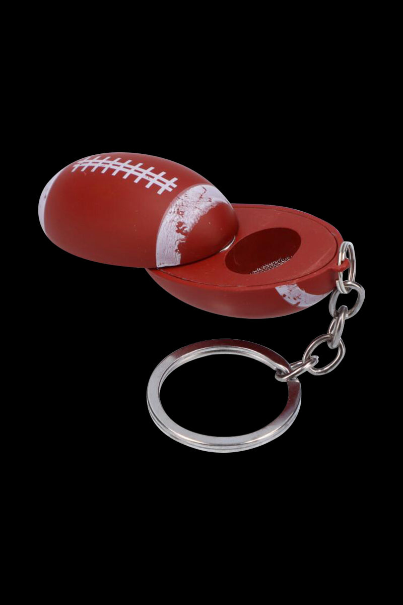 Close-up, angled view of the American Football Metal Hand Pipe with Key Chain showing a red, football-shaped metal body split open to reveal the bowl and attached silver key ring.