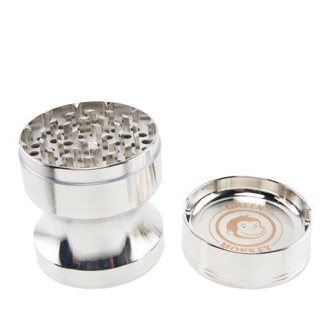 Studio-lit, three-piece view of the Green Monkey Chacma Grinder with Ashtray in polished silver showing teeth and branded ashtray insert
