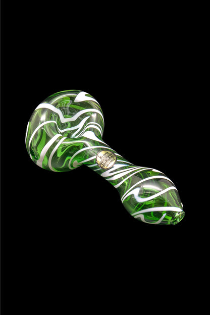 Green and white glass cannabis pipe isolated on a black background.