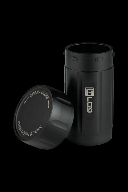 Black cannabis storage container with a twist-top lid displaying opening/closing instructions.