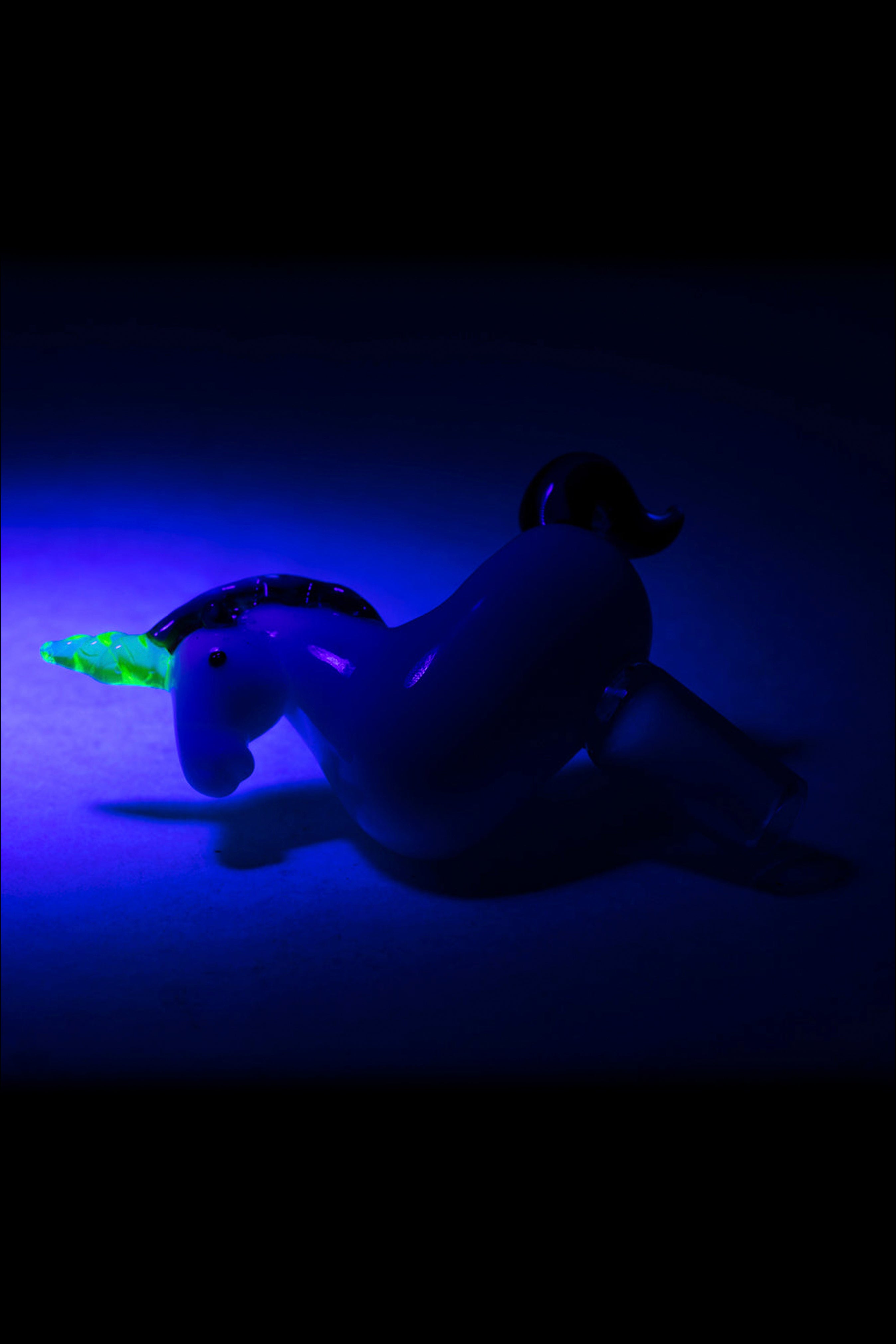 Glass pipe shaped like a unicorn with a glowing green horn, set against a dark blue background.