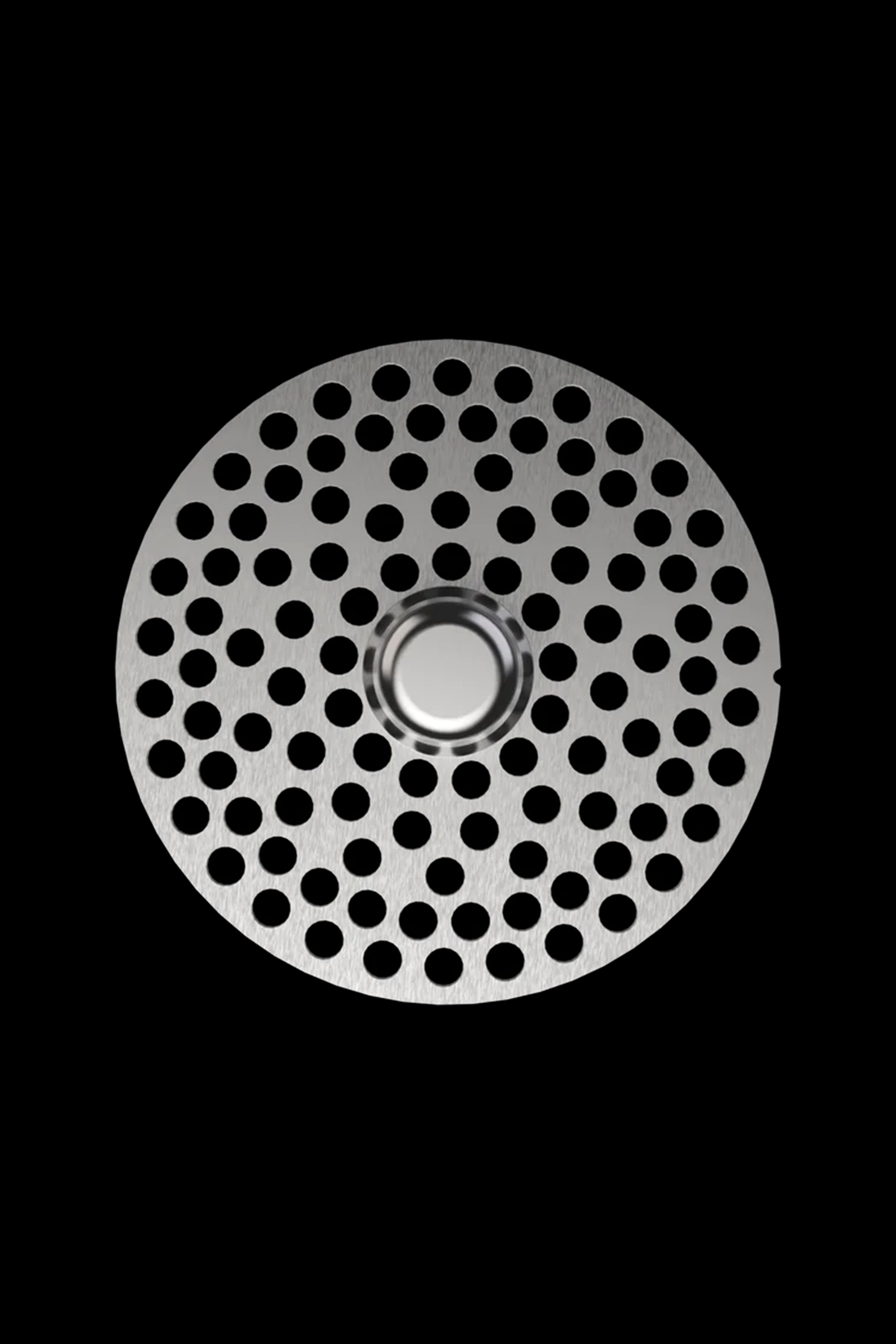 Metal grinder plate with numerous small holes, isolated on black.