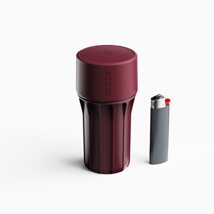 Close-up top-down view of the burgundy STAZE PRESERVE canister with vertical ribbing beside a gray lighter.