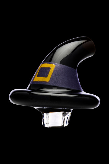 Glass dab cap shaped like a witch's hat with a golden buckle, isolated on black.