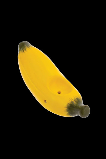 Yellow glass banana-shaped pipe with visible holes, isolated on a black background.