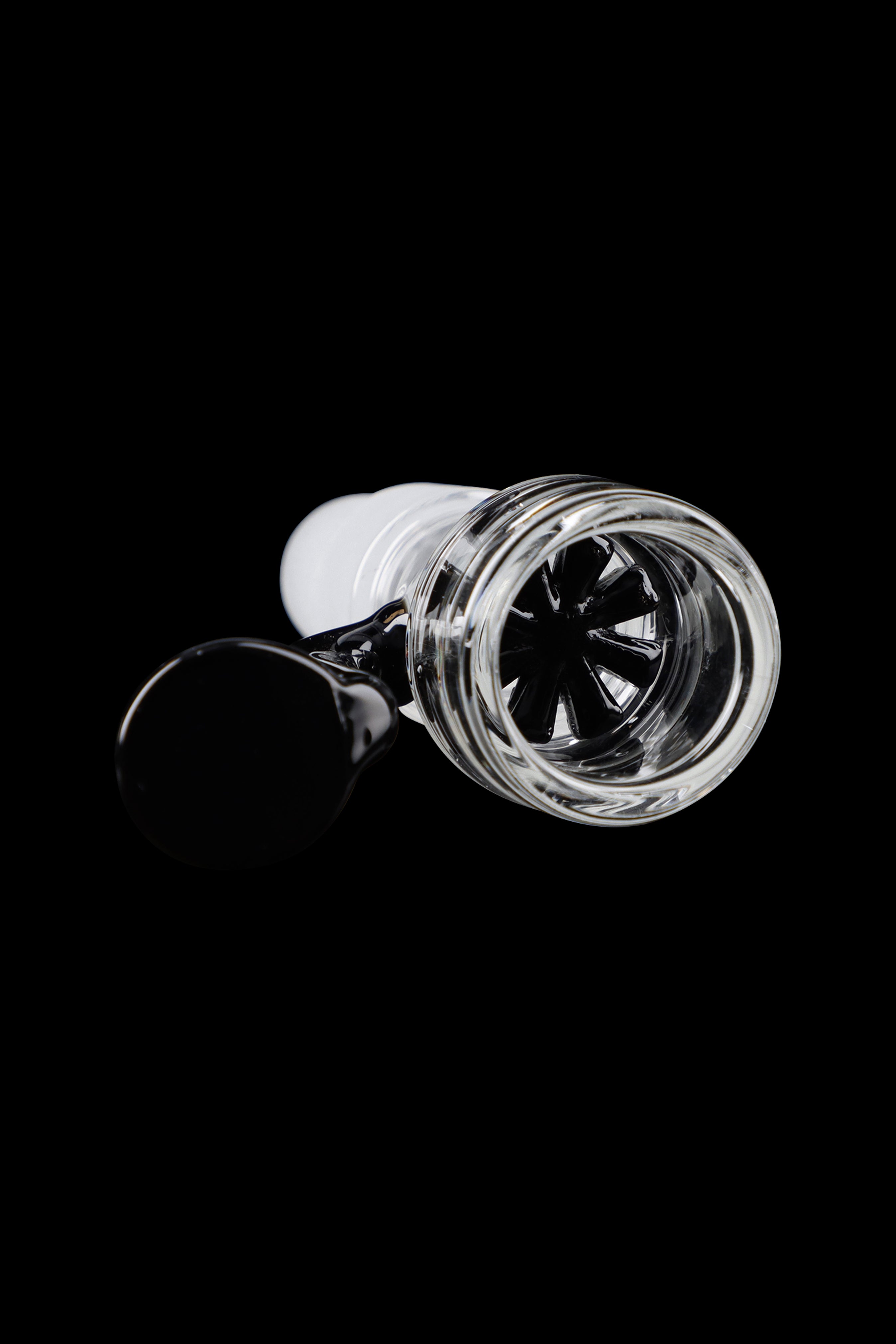 Glass cannabis bowl with intricate internal diffusion slits, isolated on a black background.