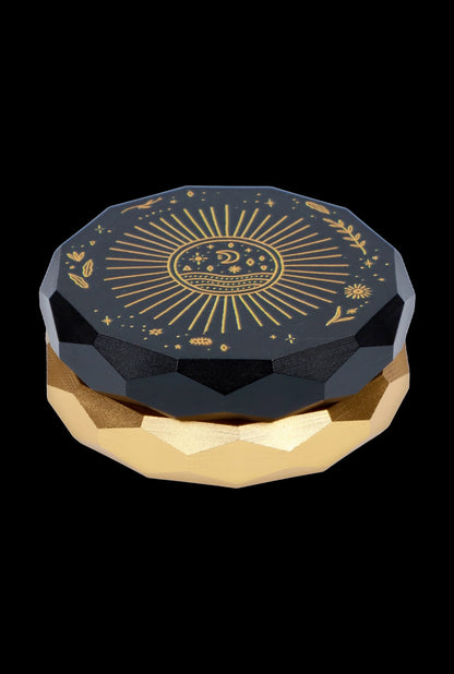 Black and gold cannabis grinder with celestial sun design.