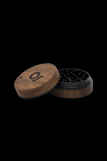 Wooden grinder with open lid, revealing metal teeth for cannabis preparation.