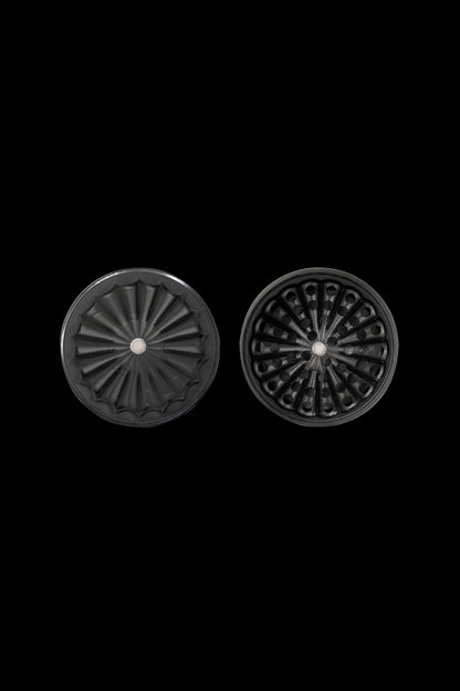 Two dark, intricately designed cannabis grinder plates against a black background.