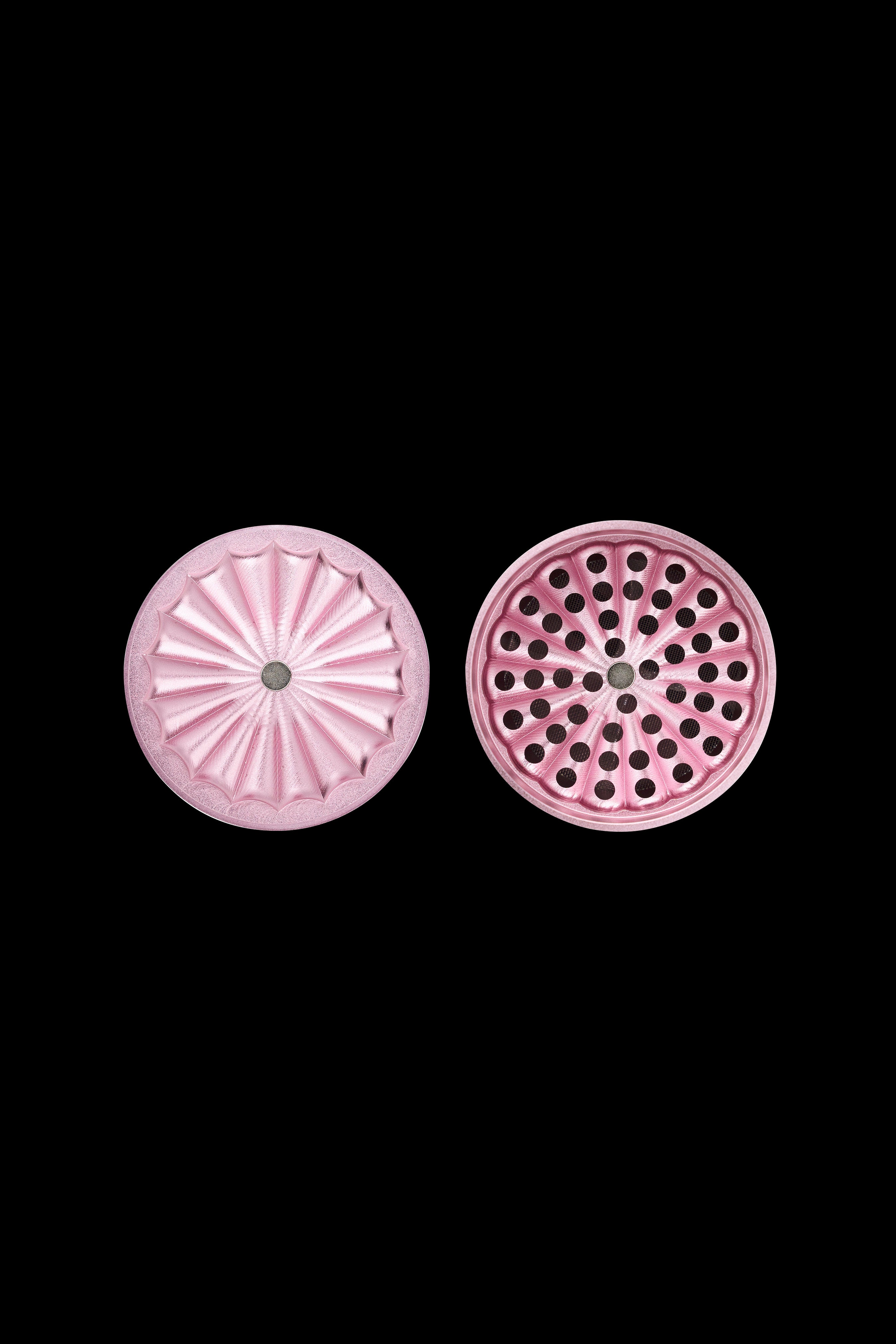 Pink cannabis grinder parts with textured and perforated surfaces on a black background.