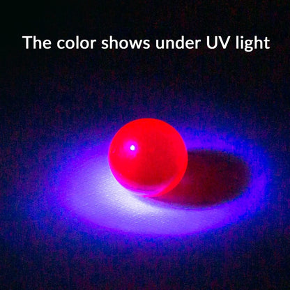 Single overhead view of a glowing red sphere on a dark surface under UV light, the Stash Shack Ruby Terp Pearls illuminated with a purple halo.