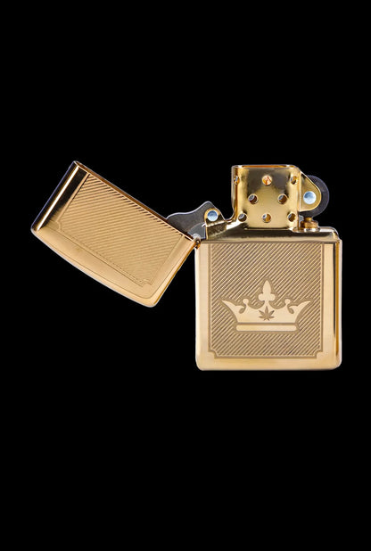 Gold lighter with a crown and cannabis leaf emblem, open against a black background.