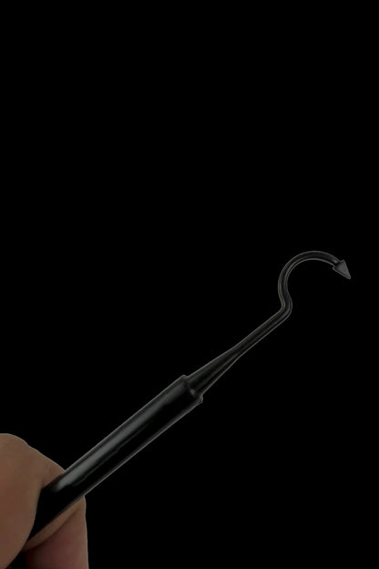 Black dab tool held in a hand against a black background.