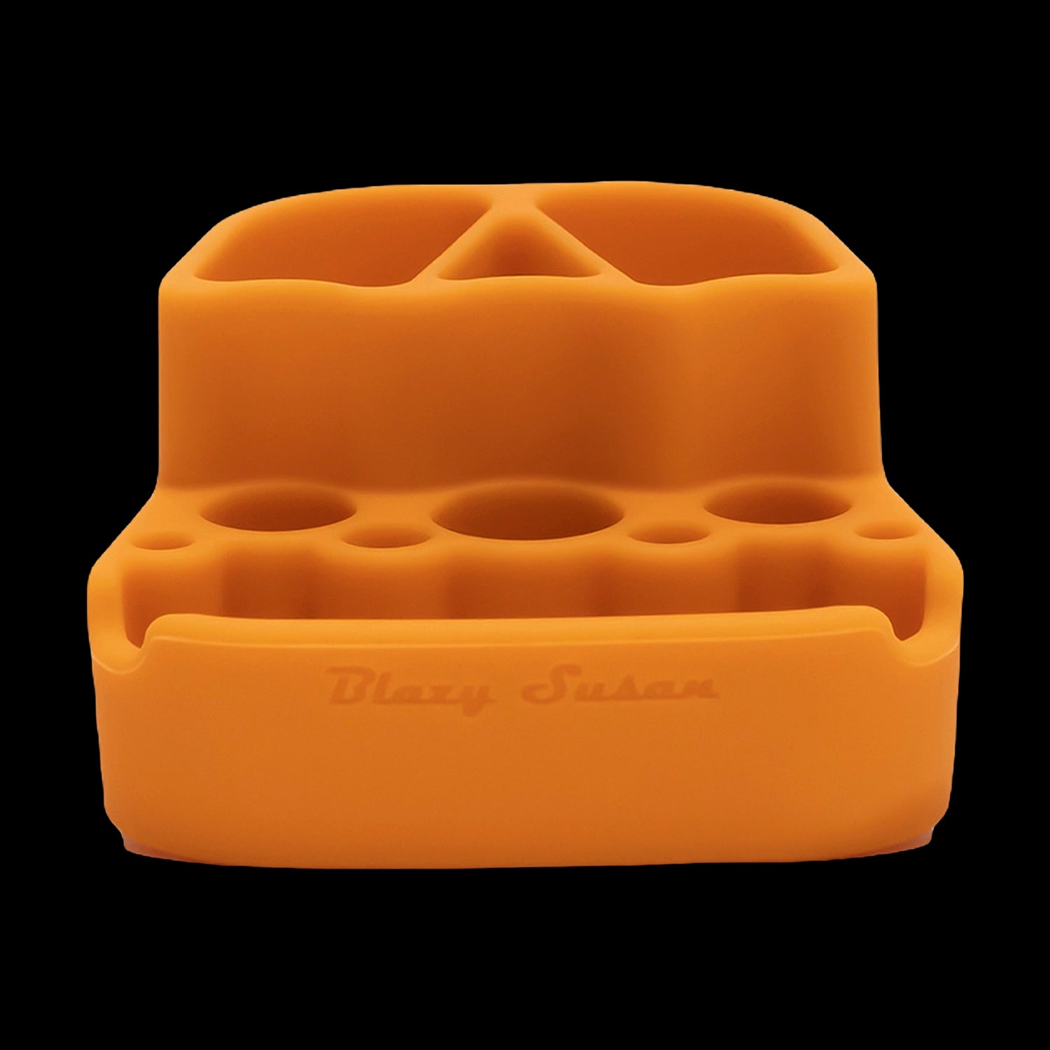 Close-up front view of the orange Blazy Susan Dab Station showing its molded silicone wells and slots against a black background.