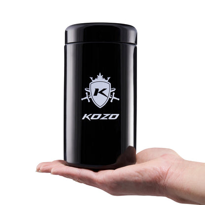 A hand holding a sleek, black cylindrical container with a cannabis leaf-themed logo and the text “KOZO.”