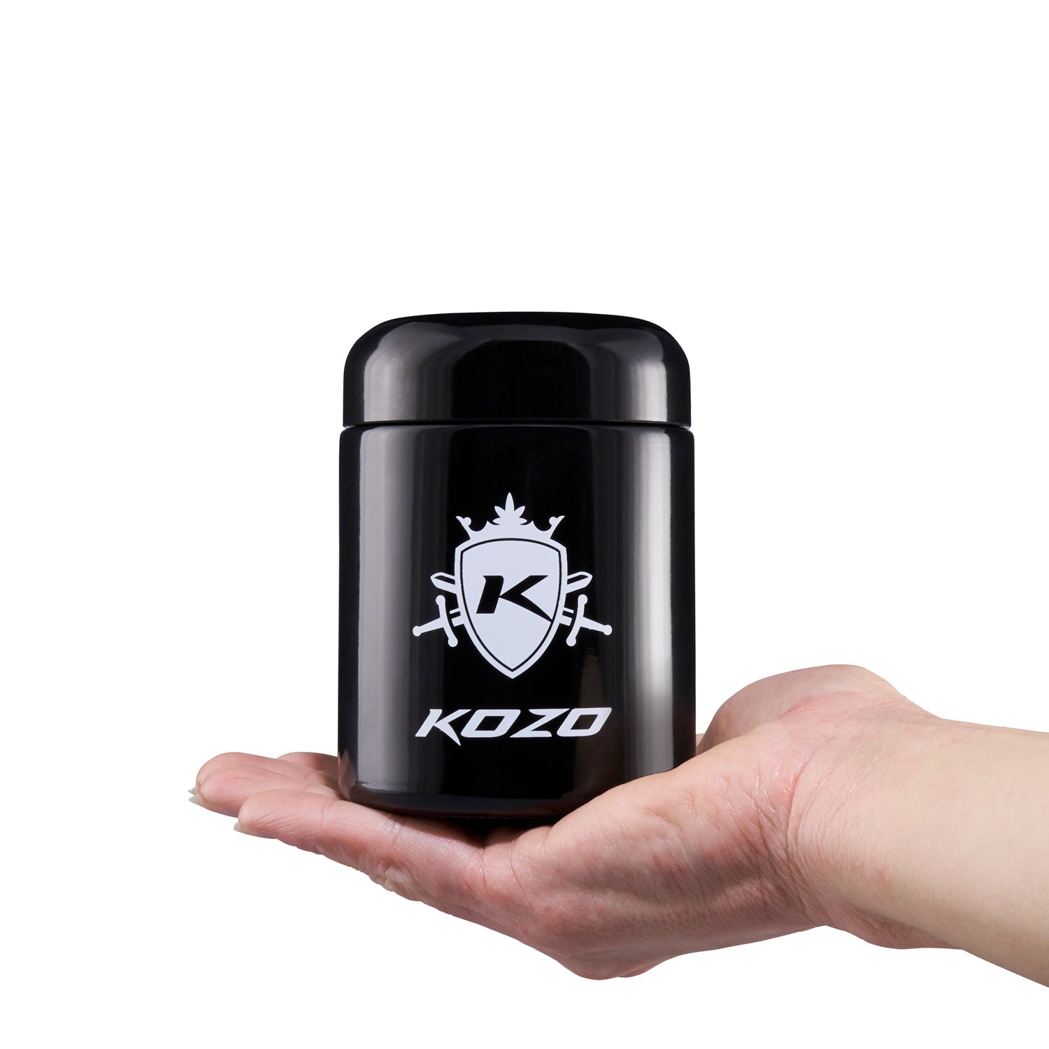 Black cannabis concentrate container with “KOZO” branding held in a hand.