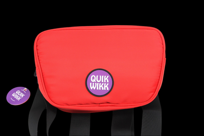 Close-up front view of a red Quik Wikk Fanny Pack with a centered purple circular logo and visible black straps against a black background
