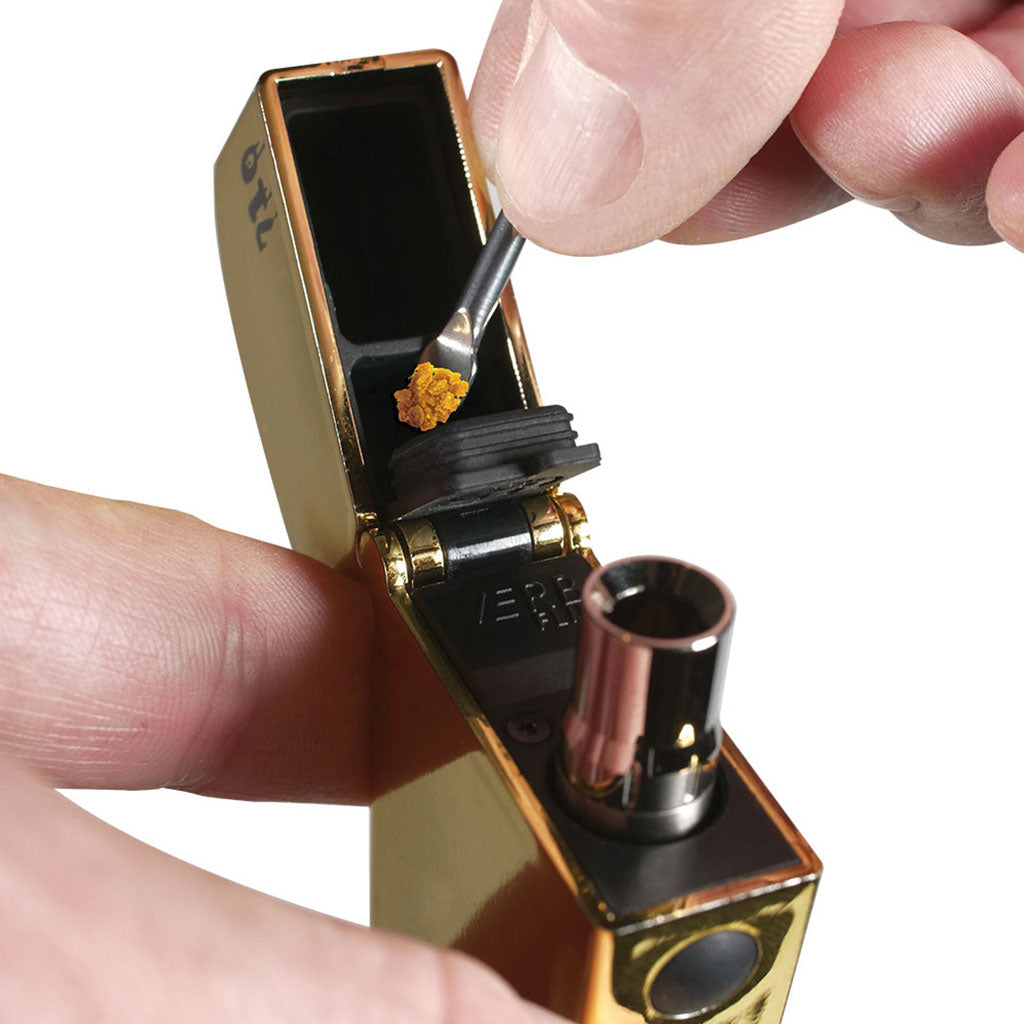 Close-up of a hand loading concentrate into the open chamber of the RYOT® 3 Pack Of Extra Coils For 710 Wax Tank - New, shown at a slight angled top view against a white background.