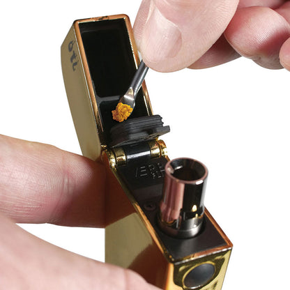 Close-up of a hand loading concentrate into the open chamber of the RYOT® 3 Pack Of Extra Coils For 710 Wax Tank - New, shown at a slight angled top view against a white background.