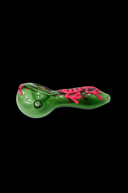 Green glass pipe with pink accents, side view against a black background.
