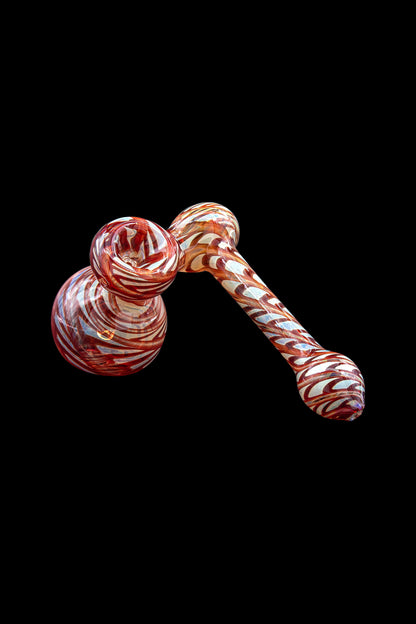 Red and white swirled glass bubbler for cannabis use, isolated on a black background.