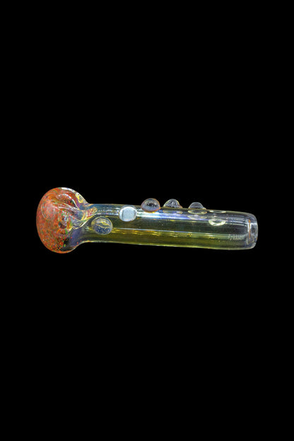 Hand-blown glass pipe with vibrant red and gold accents, isolated on a black background.