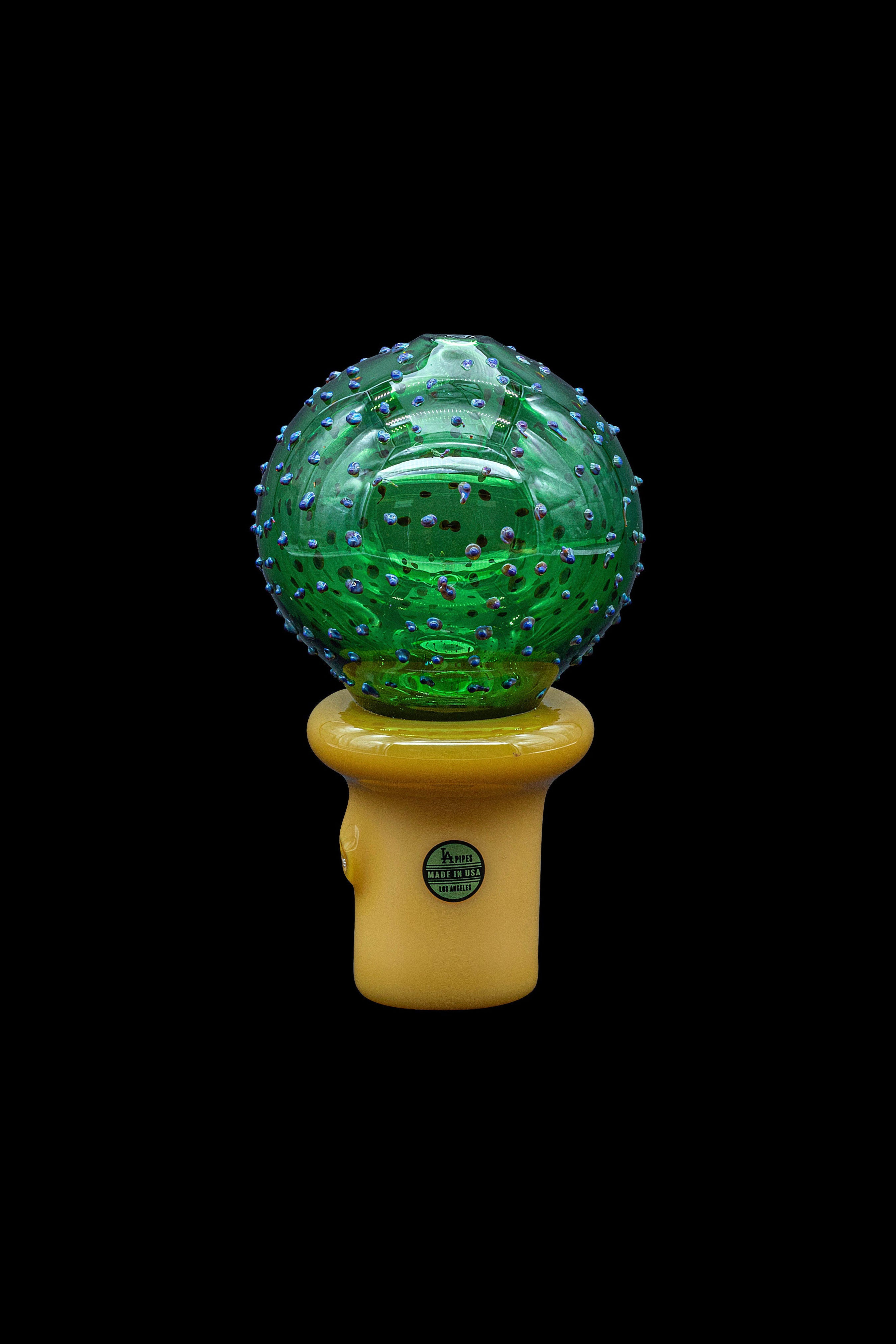 Green, spherical cannabis water pipe with a textured surface, mounted on a yellow base with a “Made in USA” label.