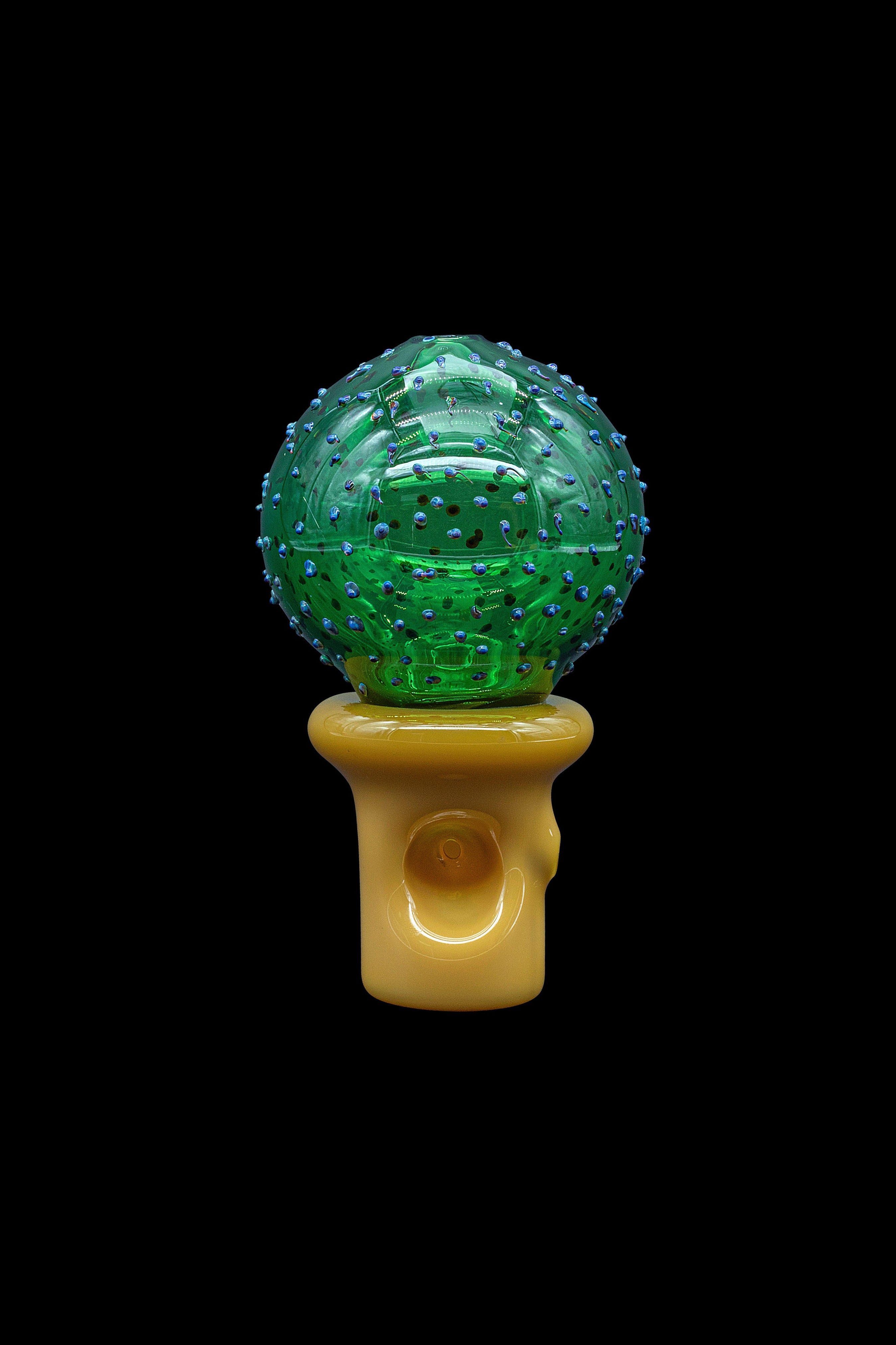 Green and blue patterned glass cannabis water pipe against a black background.