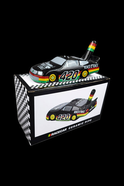A black and white checkered box containing a miniature race car-shaped ceramic pipe branded with “420” and “Roast & Toast.”