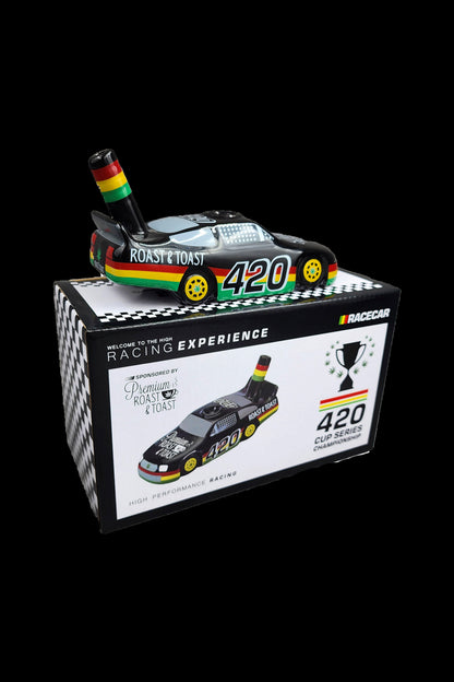 A promotional box for “Roast & Toast” cannabis accessories, designed as a miniature race car display with “420” branding and racing flags.