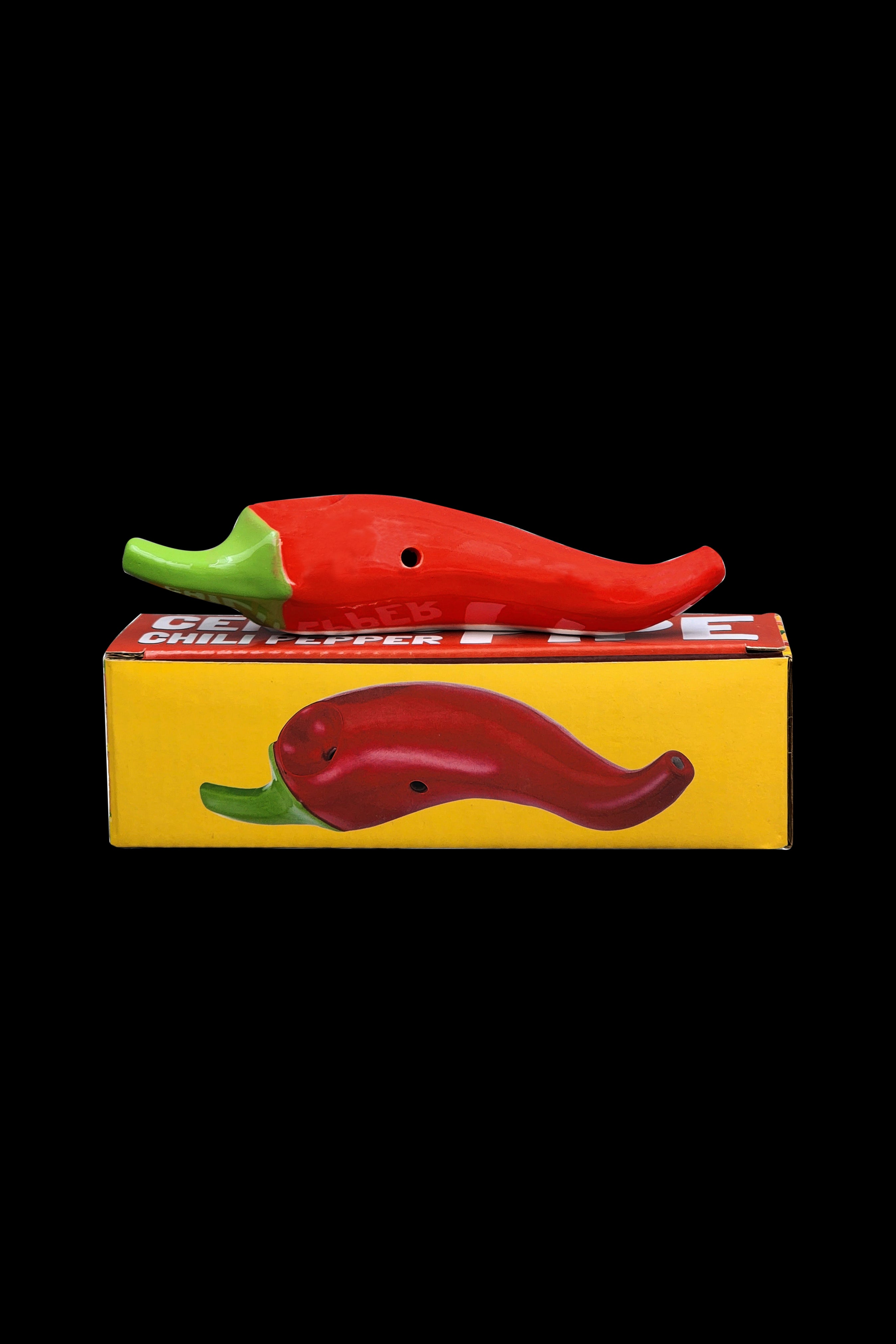 Red chili pepper-shaped smoking pipe and its packaging on a black background.