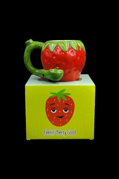Strawberry-shaped glass pipe with its branded box displaying a smiling strawberry and the text "Feelin' Berry Good."